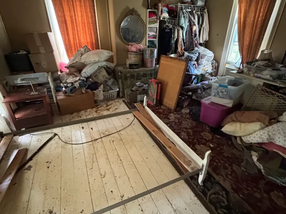 Cluttered bedroom cleanout with piled household items
